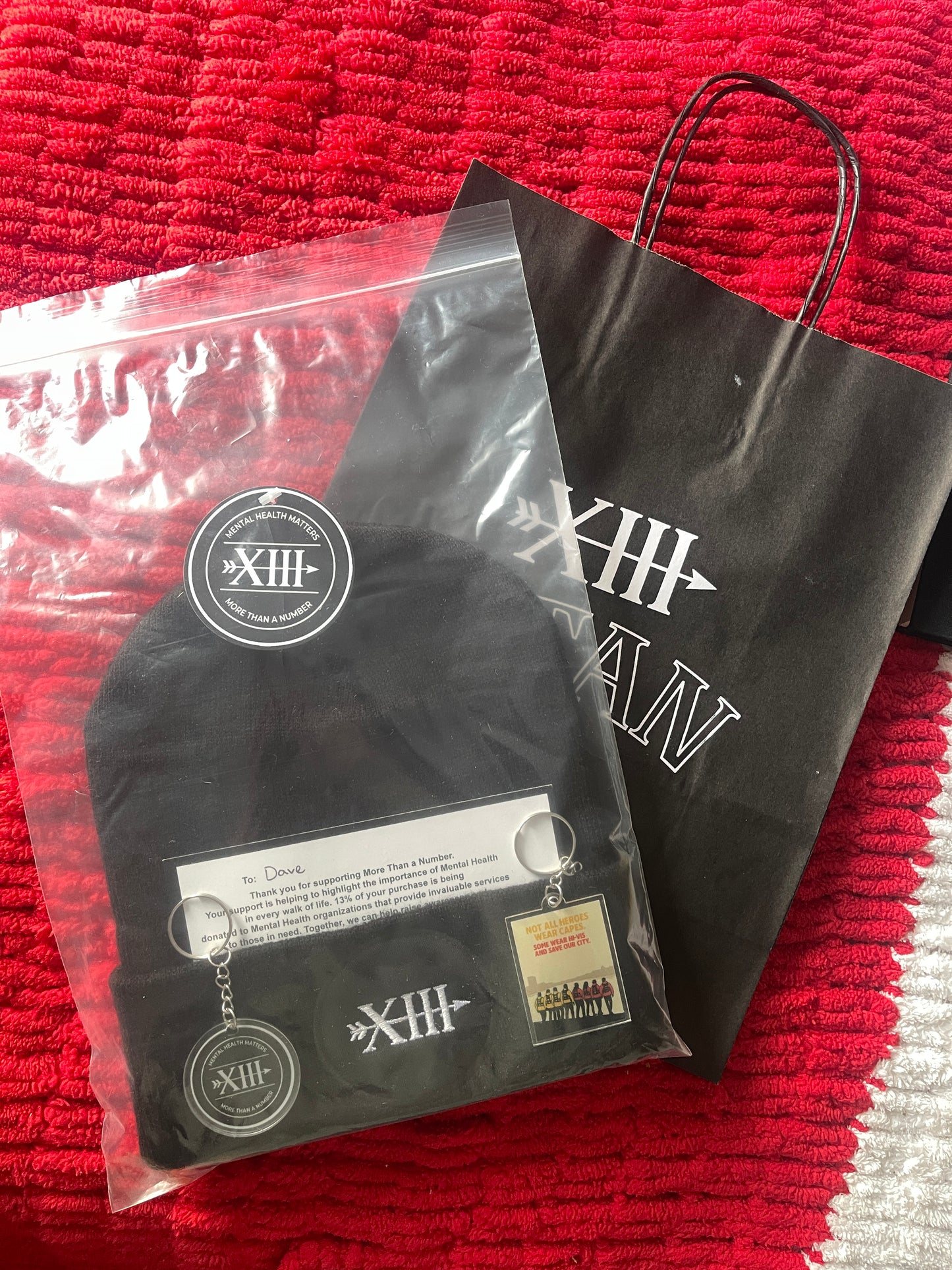 Black MTAN beanie with brand logo on a red textured surface