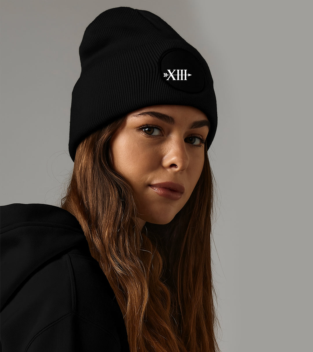 Woman wearing MTAN black beanie with a logo on a gray background